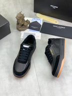 Side view of black lace-up sneakers with gum-style rubber sole