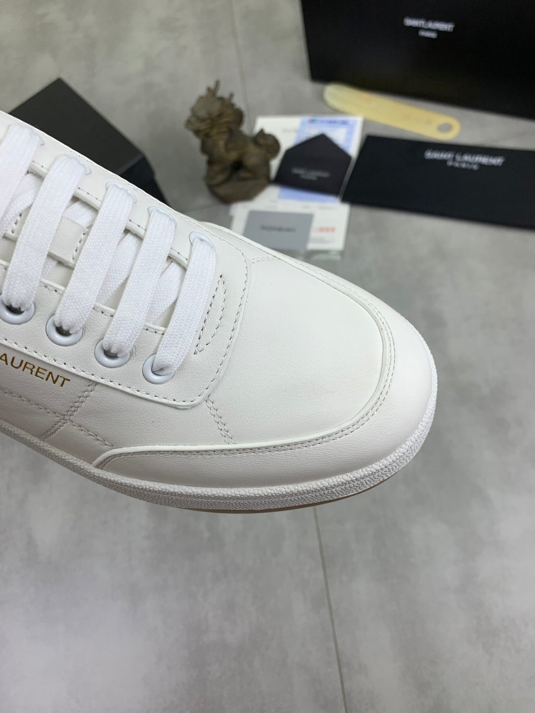 Close-up of white sneaker upper with white laces and stitched detail.
