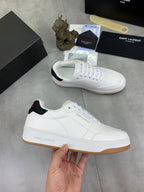 White low-top sneakers with white laces, black heel collar, and gum soles.