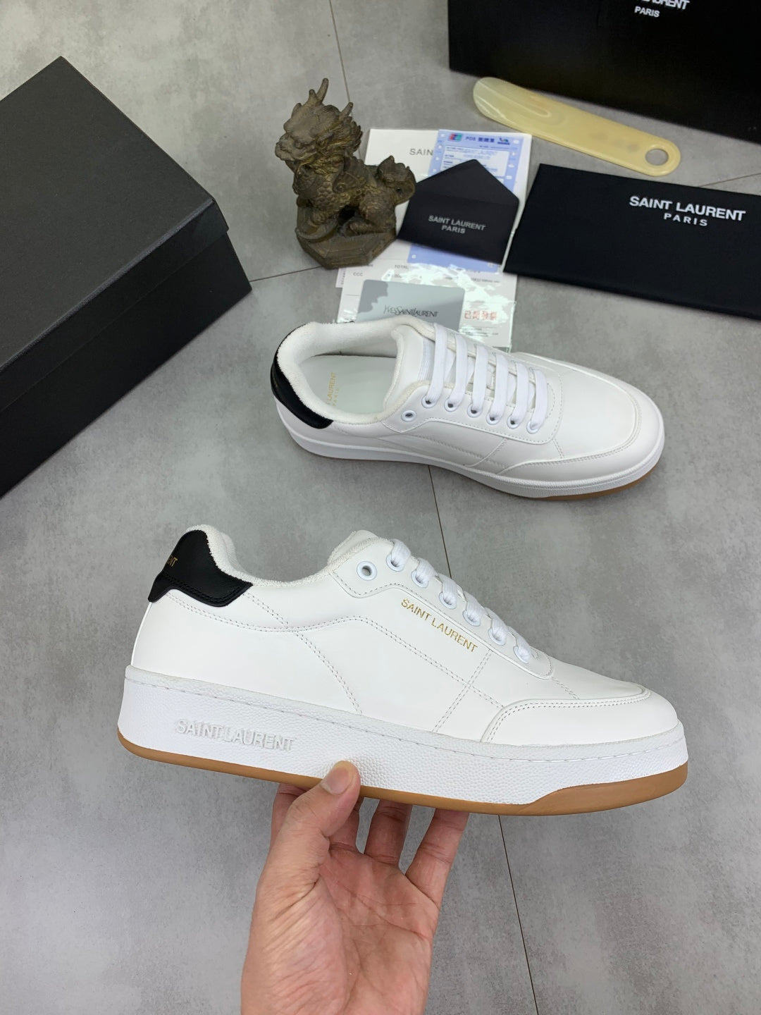 White low-top sneakers with white laces, black heel collar, and gum soles.