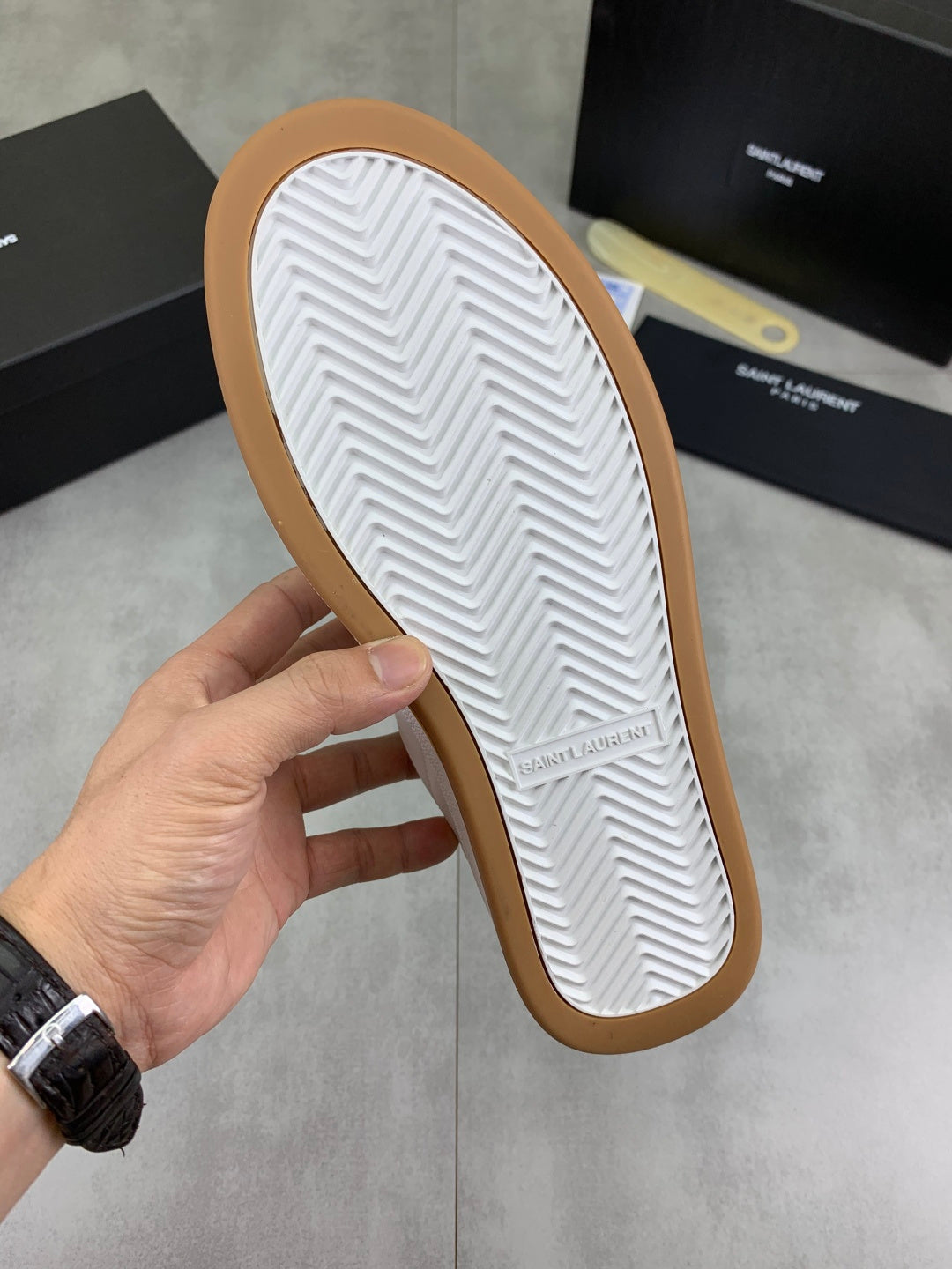Unisex sneaker outsole, white tread with brown rubber edge and chevron pattern.