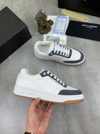 Unisex low-top sneakers held, white uppers with navy accents and gum sole.