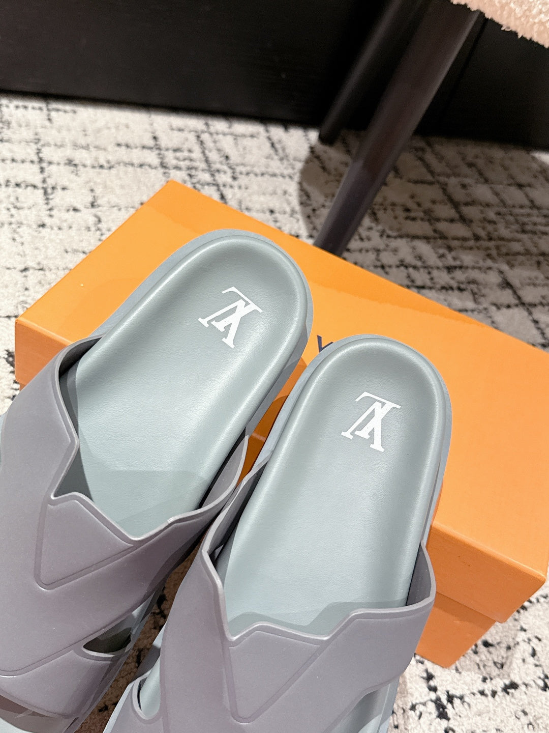Light blue Louis Vuitton sandals with LV logo on footbeds, on orange box
