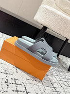 Light blue Louis Vuitton slide sandals with wide strap, shown on orange box from side