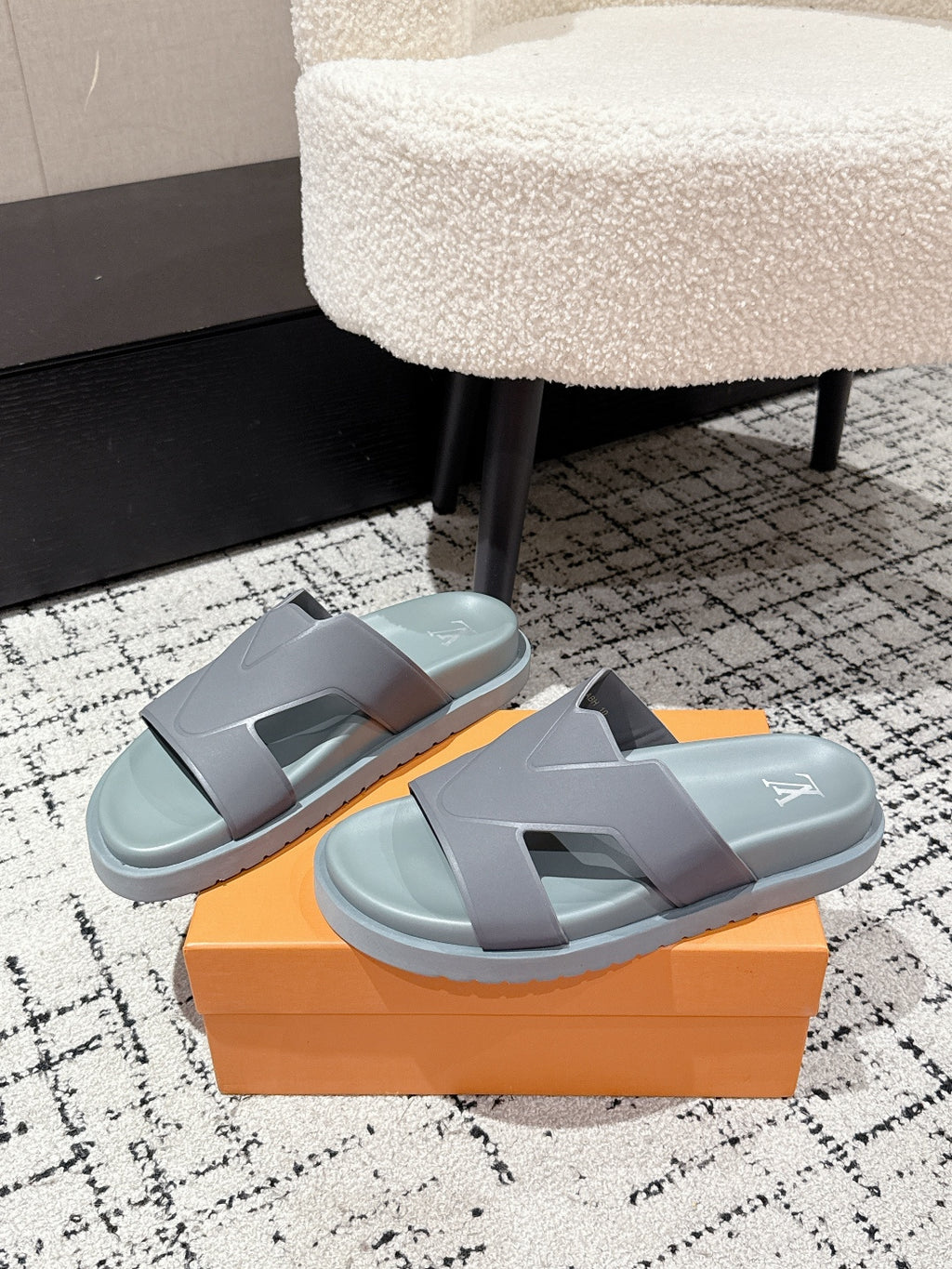 Light blue Louis Vuitton slide sandals with wide strap and LV logo, on orange box