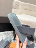 Light blue Louis Vuitton slide sandal with wide strap, held above orange box