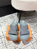 Light blue Louis Vuitton slide sandals with wide strap and LV logo, on orange box