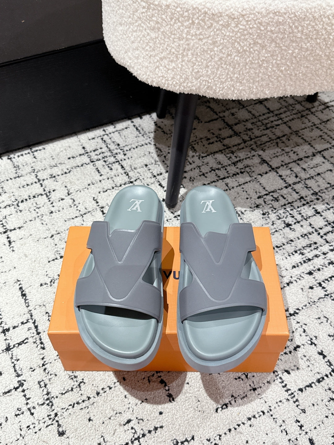 Light blue Louis Vuitton slide sandals with wide strap and LV logo, on orange box