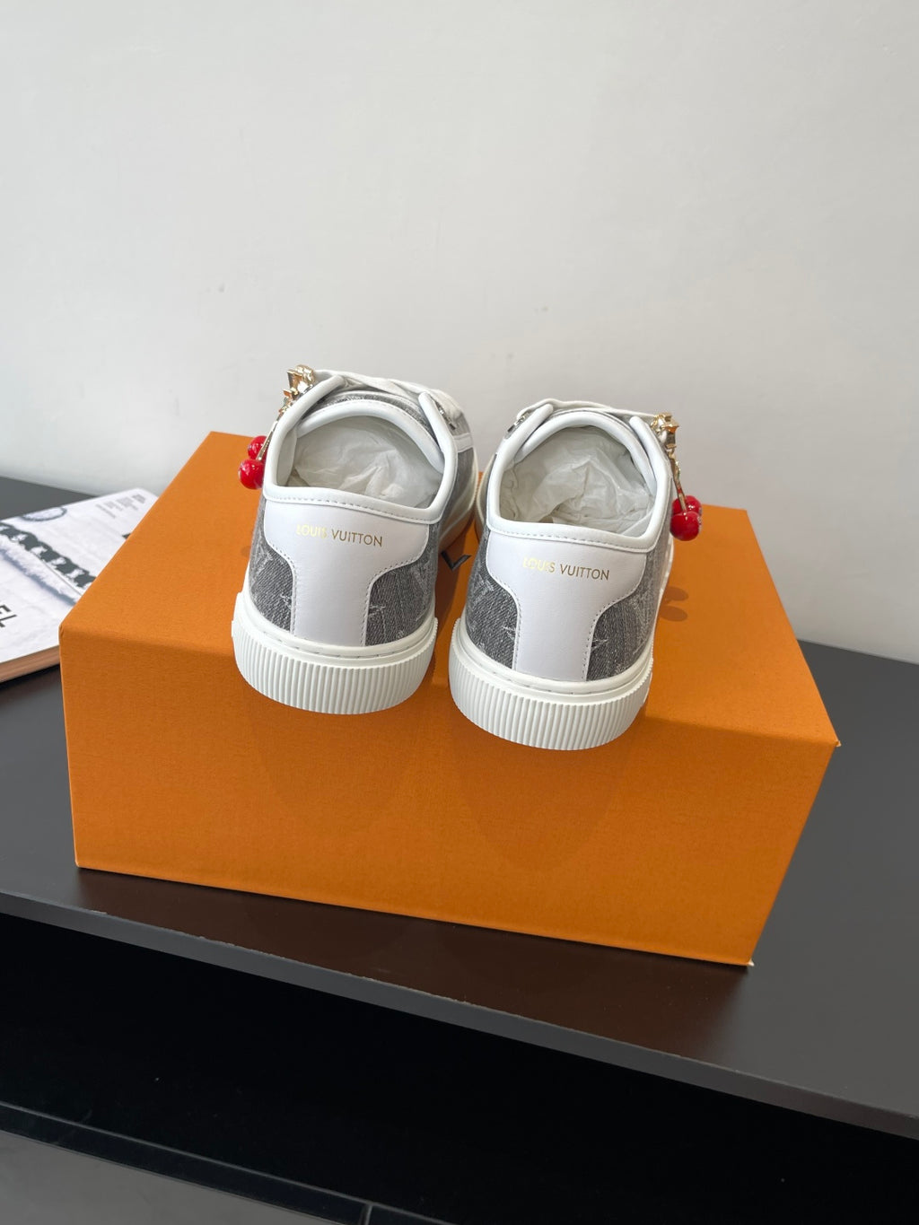 Women’s low-top sneakers viewed from back, dark monogram upper and white outsole.