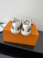 Women’s low-top sneakers viewed from back, dark monogram upper and white outsole.