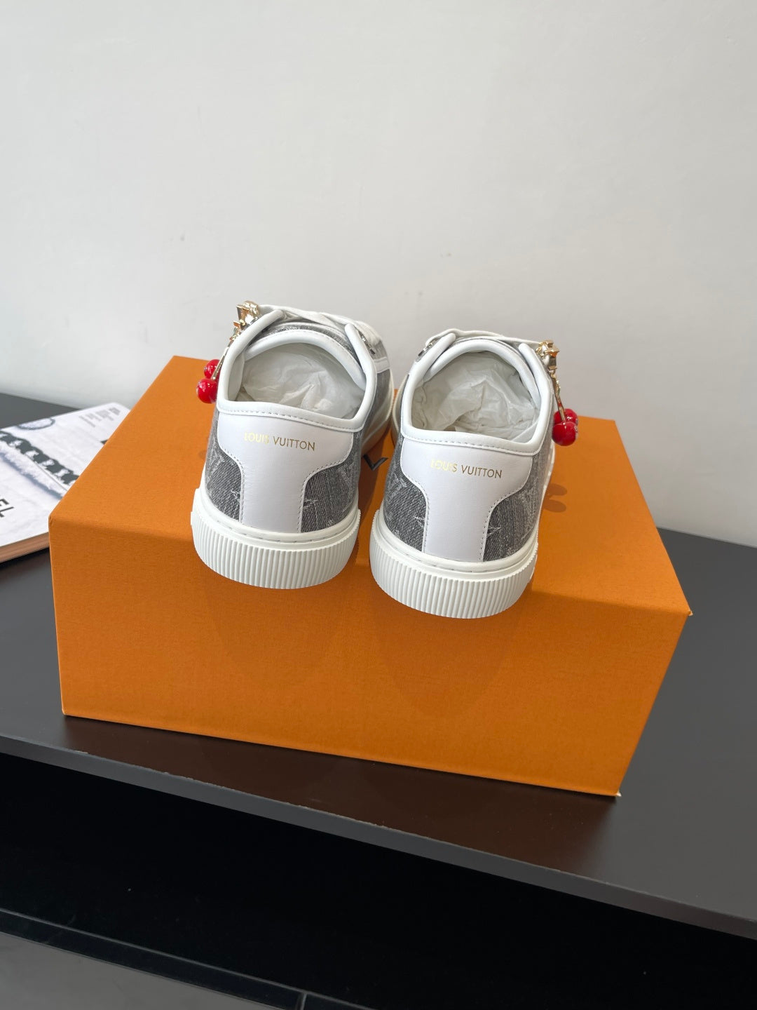 Women’s low-top sneakers viewed from back, dark monogram upper and white outsole.