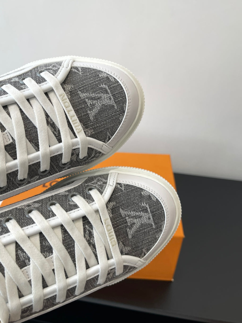 Women’s low-top sneakers, close-up of dark monogram toe and white lace rows.