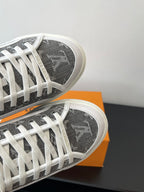 Women’s low-top sneakers, close-up of dark monogram toe and white lace rows.