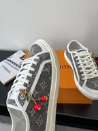 Women’s low-top sneakers, dark monogram side with red cherry charm on lace.