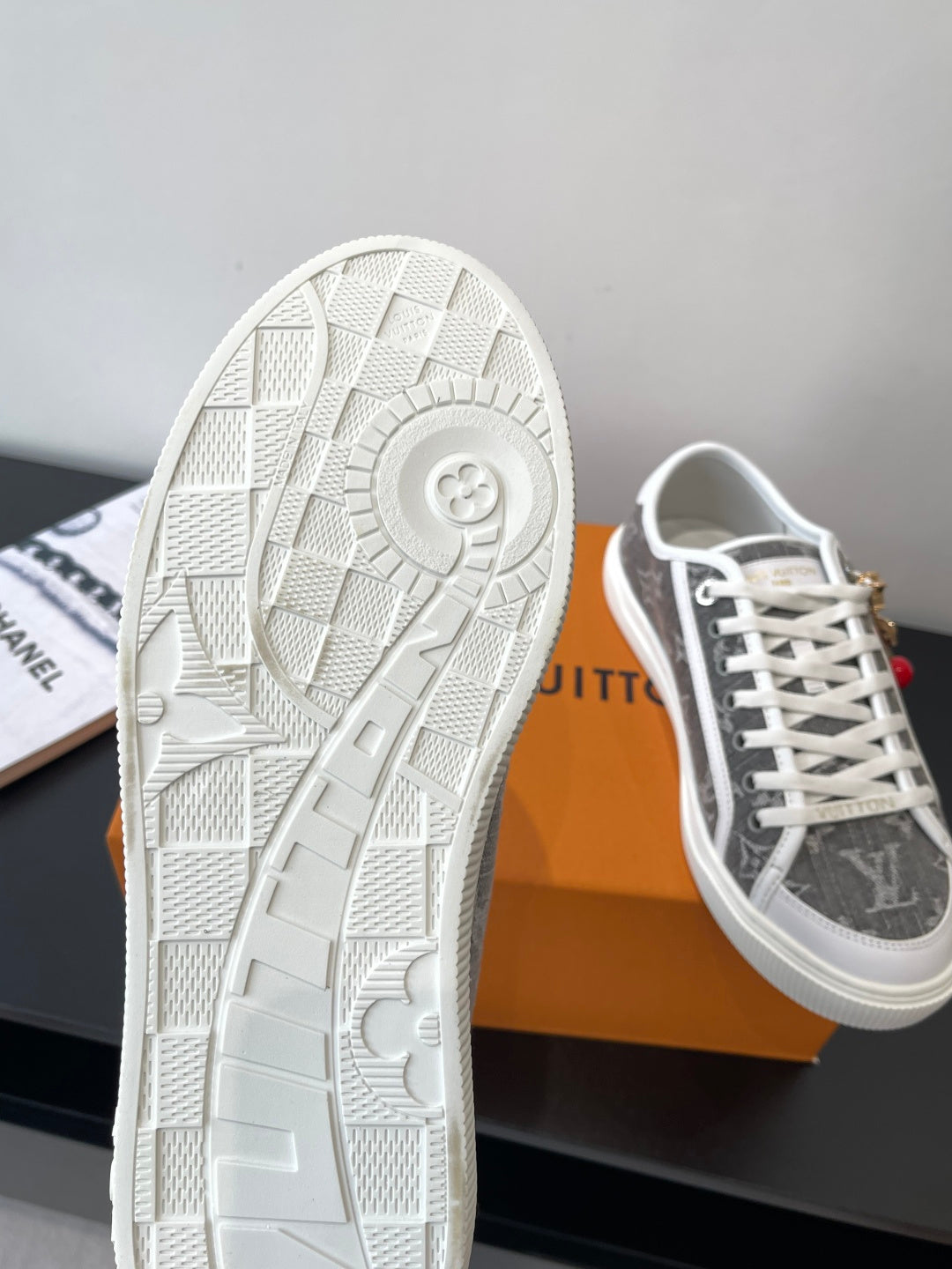 Women’s low-top sneakers, white patterned outsole and dark monogram upper.