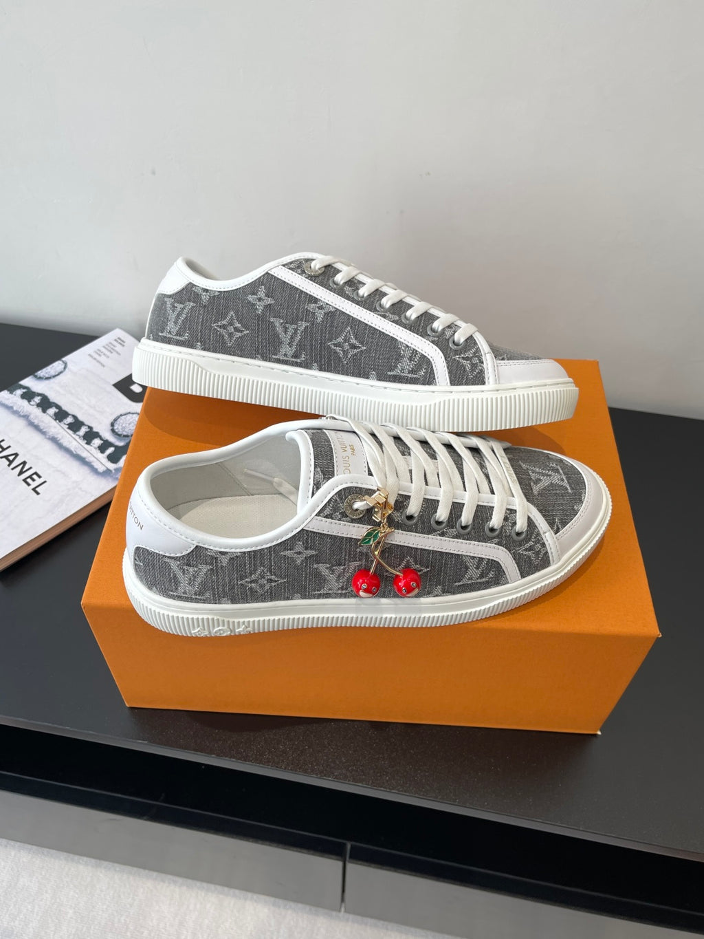 Women’s low-top sneakers, dark monogram front view with white laces and cherry charm.