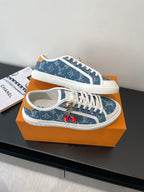 Louis Vuitton low-top sneakers angled view, blue monogram upper with white laces and red charms