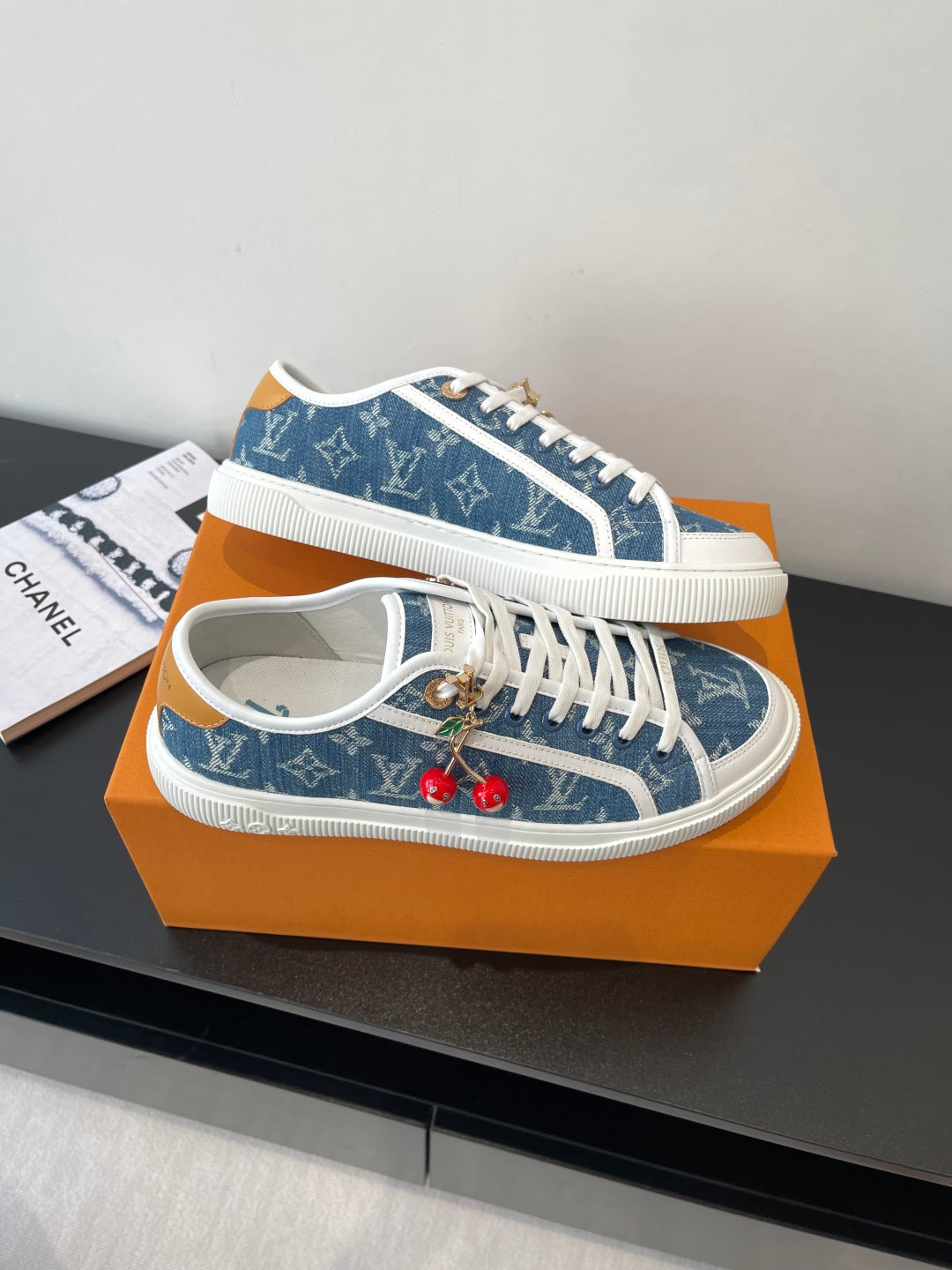 Louis Vuitton low-top sneakers angled view, blue monogram upper with white laces and red charms
