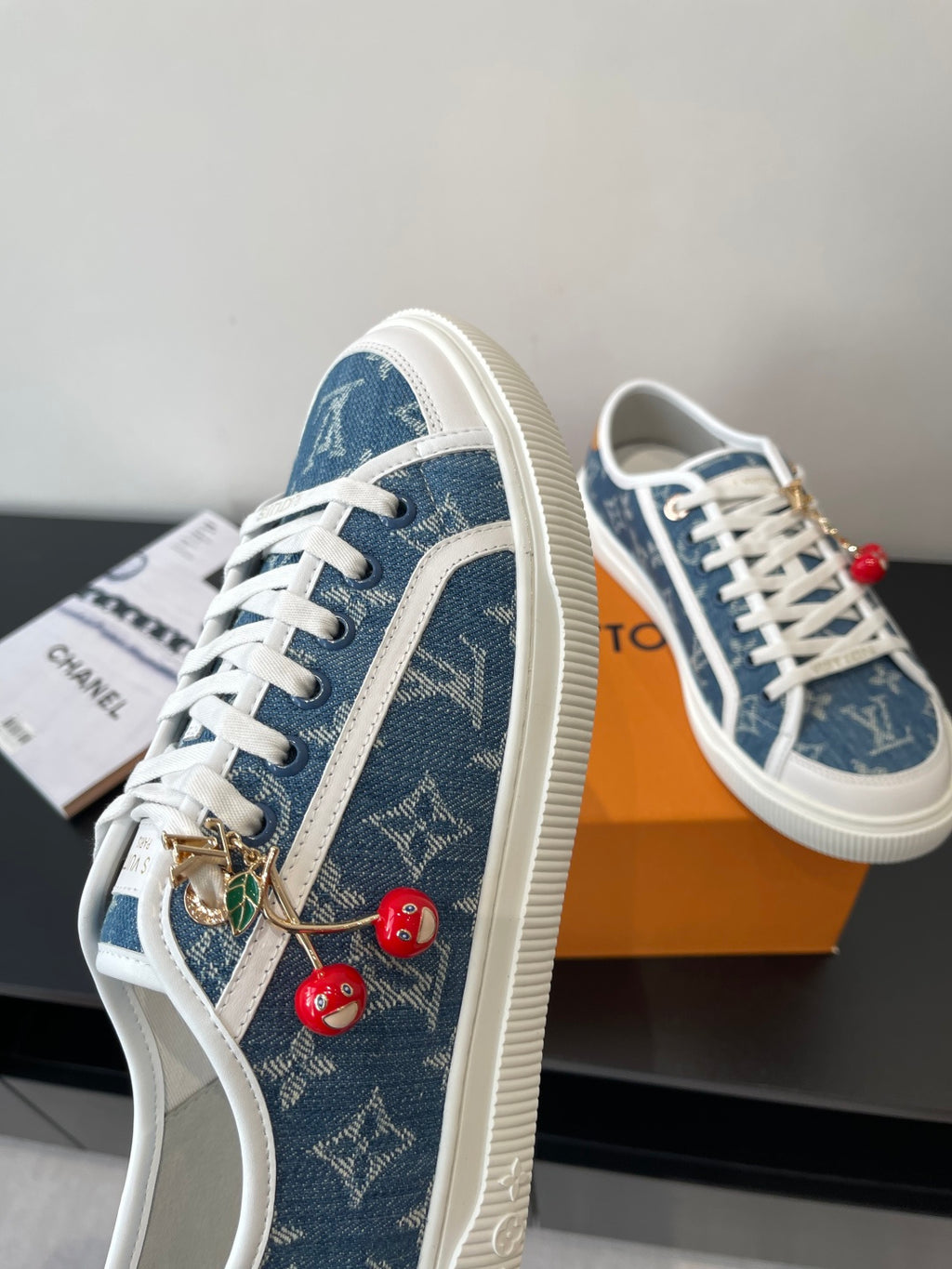 Louis Vuitton low-top sneakers with blue monogram canvas, white laces, and hanging cherry charms