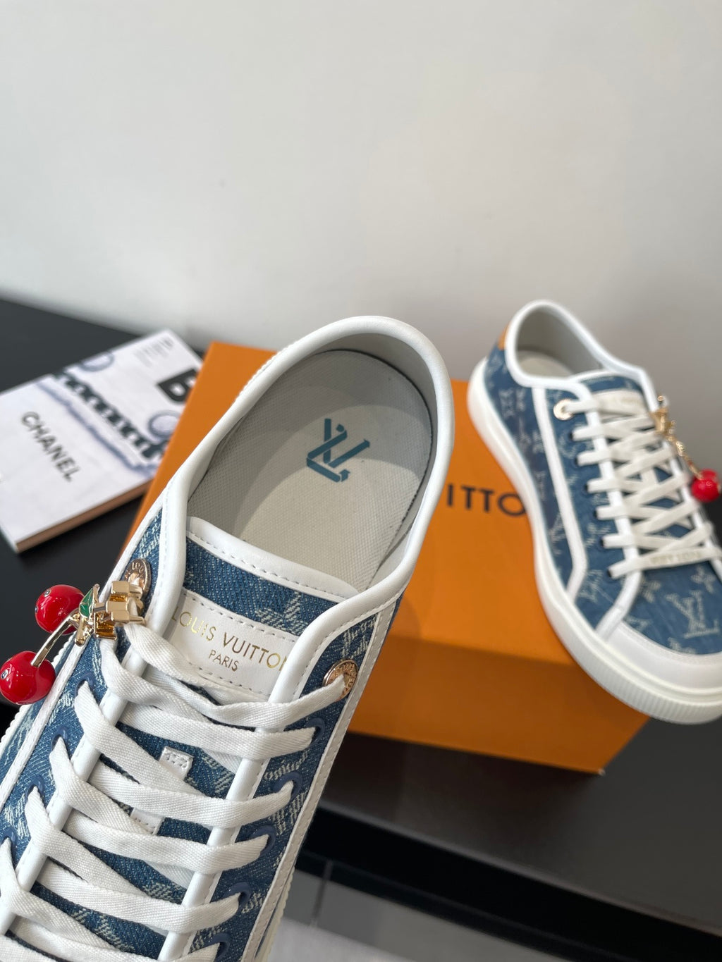 Louis Vuitton low-top sneaker with blue monogram interior, white laces, and gold charm detail