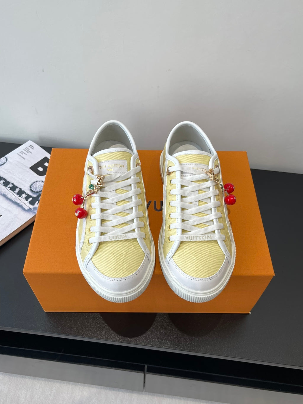 Louis Vuitton low-top sneakers with white laces, pale yellow panels, red charms
