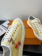 Louis Vuitton low-top sneakers, pale yellow side with metal zipper pull and red charms