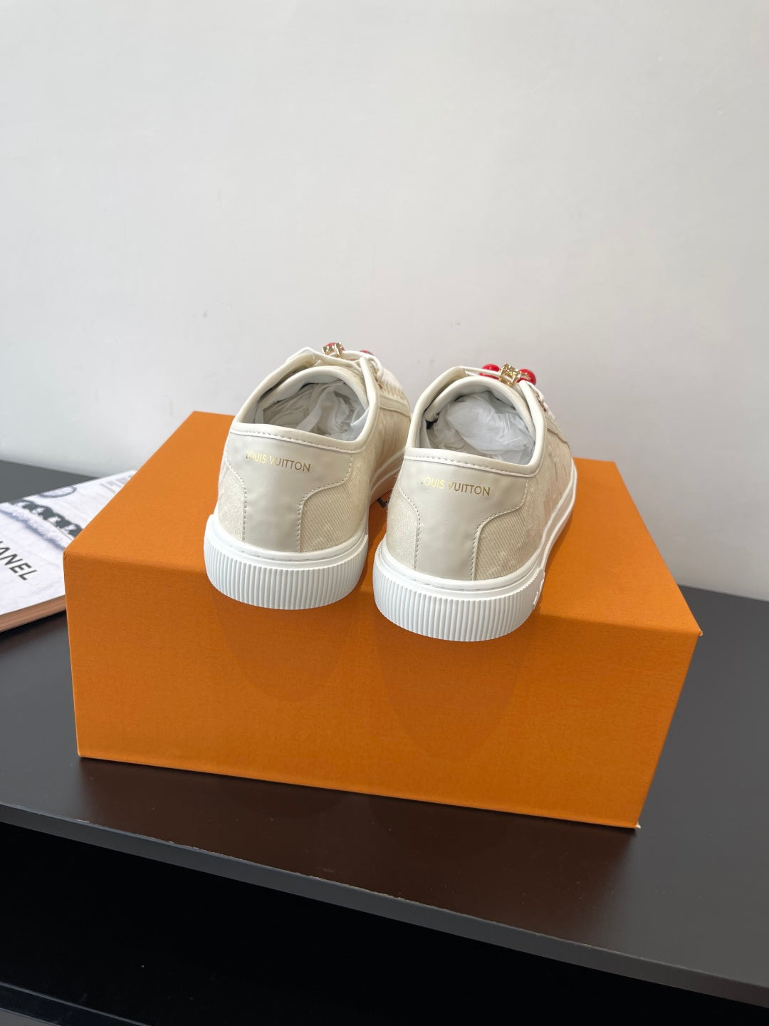 Women's Louis Vuitton sneakers, back view pair on box with white rubber sole.