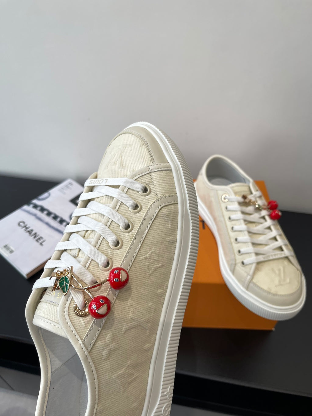 Women's Louis Vuitton sneakers, side view with red bead charm cluster and white rubber sole.