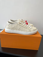 Women's Louis Vuitton sneakers on orange box, side view with red bead charms.