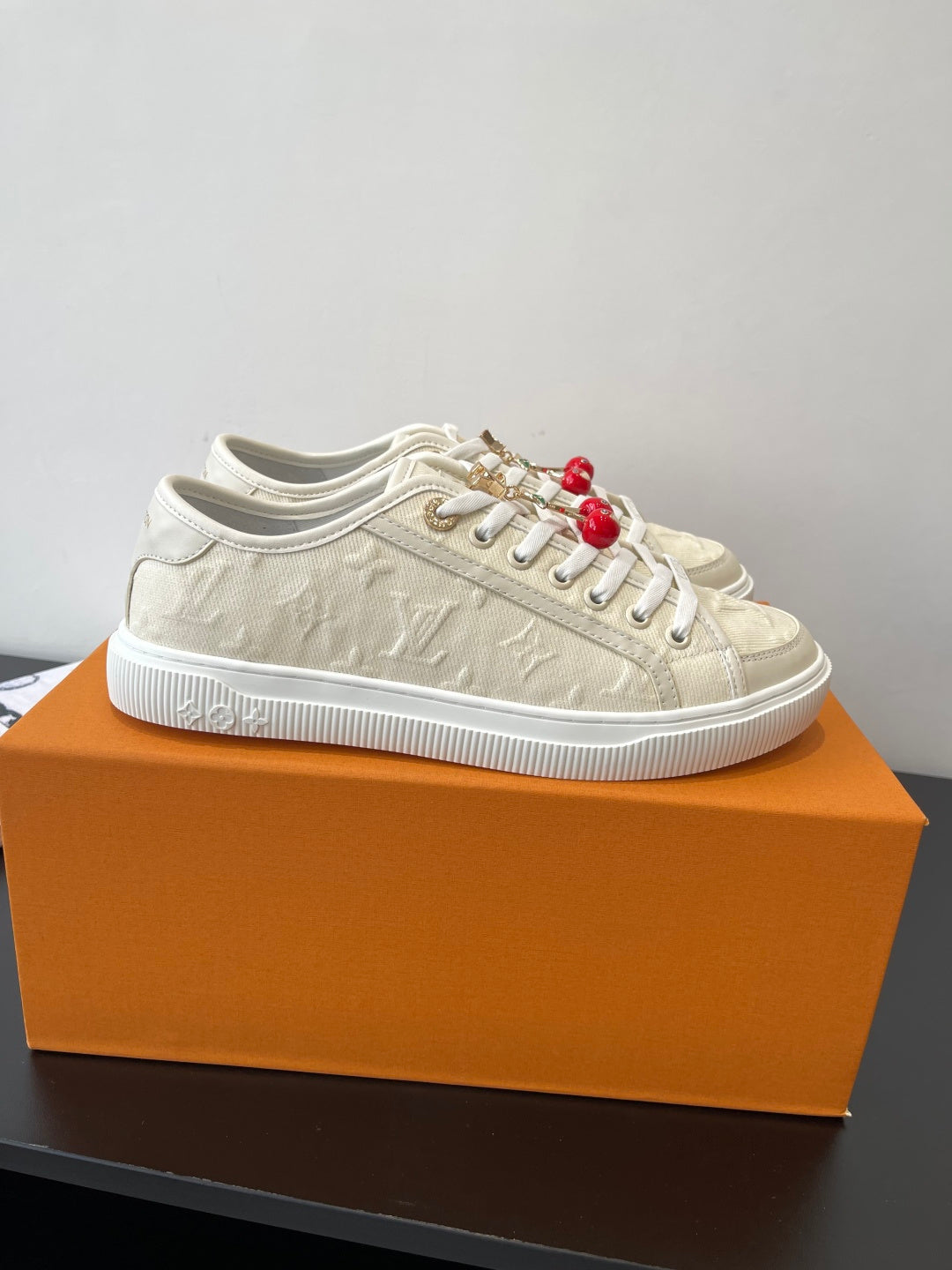 Women's Louis Vuitton sneakers on orange box, side view with red bead charms.