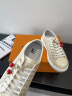 Women's Louis Vuitton sneakers, close-up of side with red bead and hardware charm details.