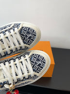 Louis Vuitton ladies sneakers close-up, navy monogram canvas, white laces, red charm accents