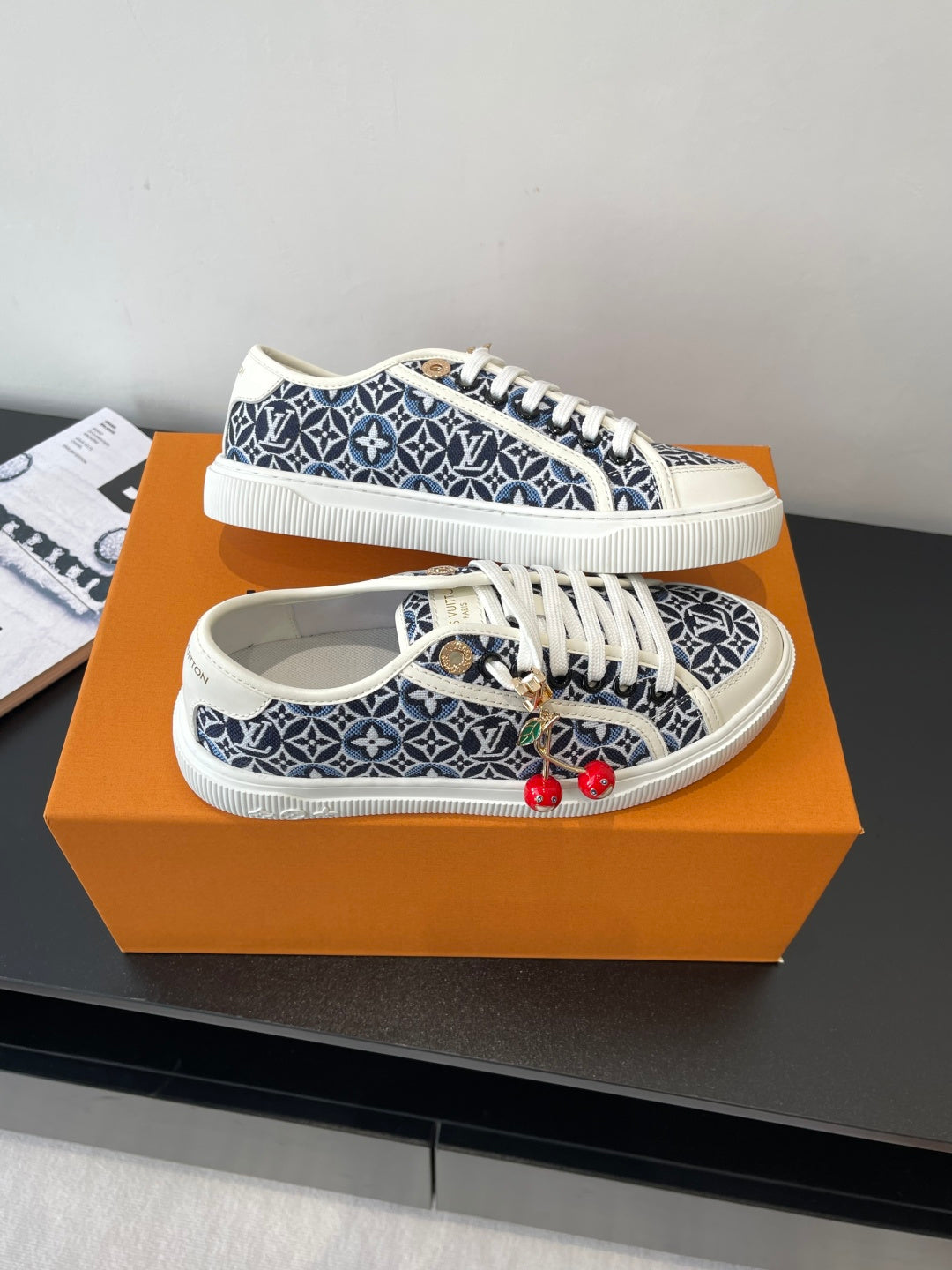 Louis Vuitton ladies sneakers on display, navy monogram print, white laces, red cherry charms
