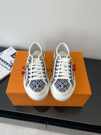 Louis Vuitton ladies sneakers with navy monogram print, white laces, red charm details