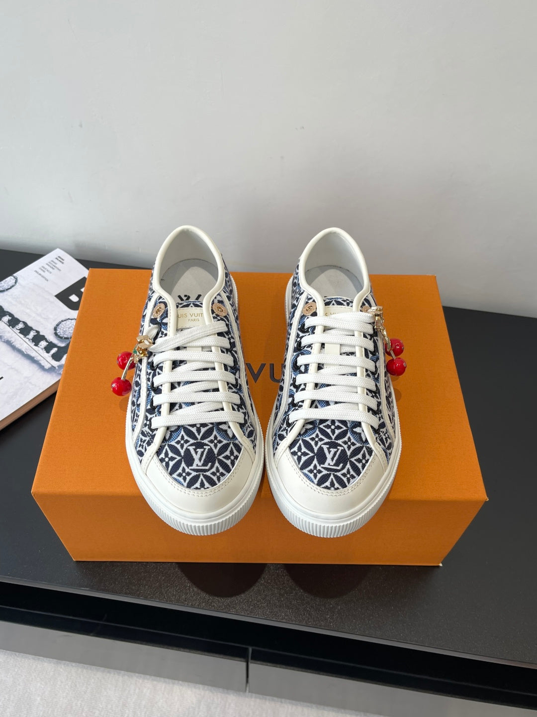 Louis Vuitton ladies sneakers with navy monogram print, white laces, red charm details