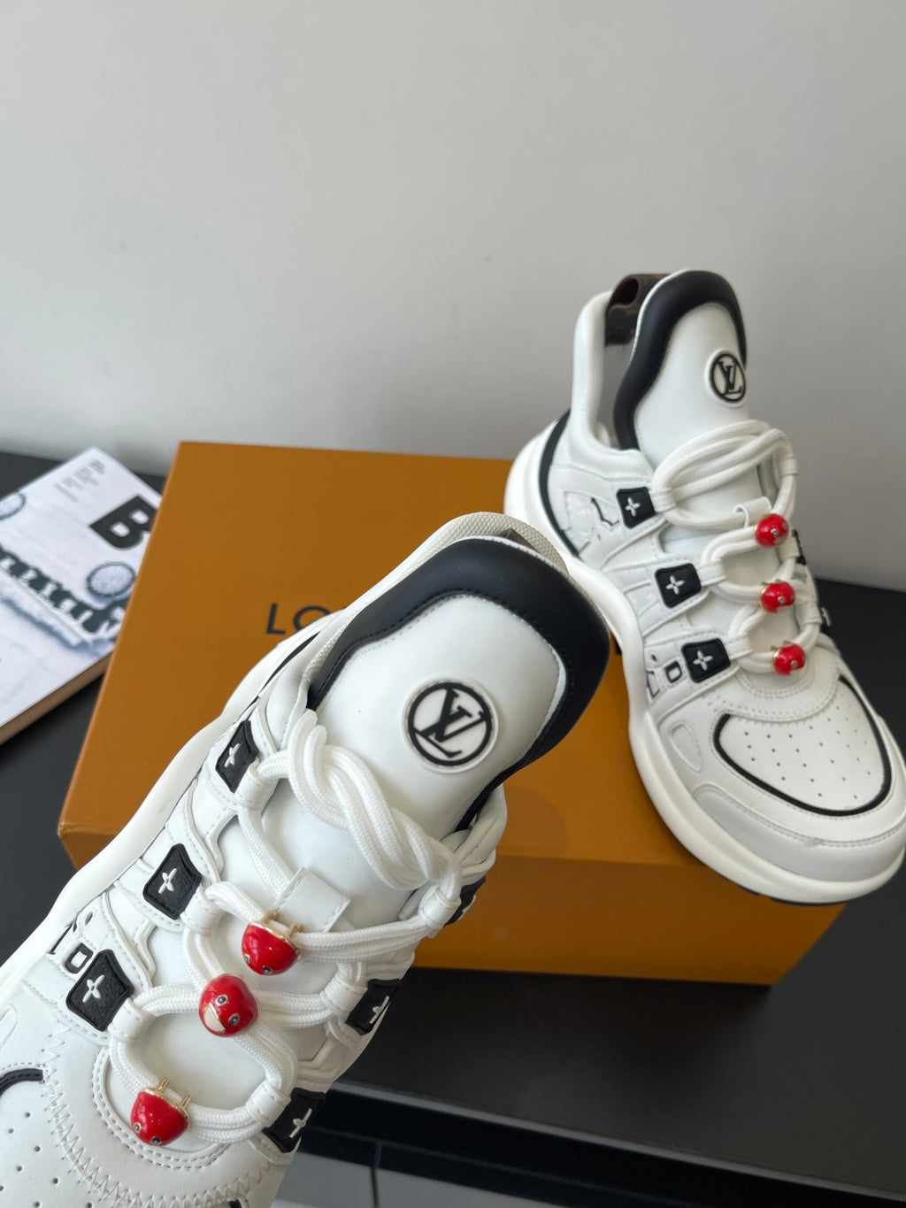 White sneakers with black inner lining, LV round logo, red beaded lace pulls