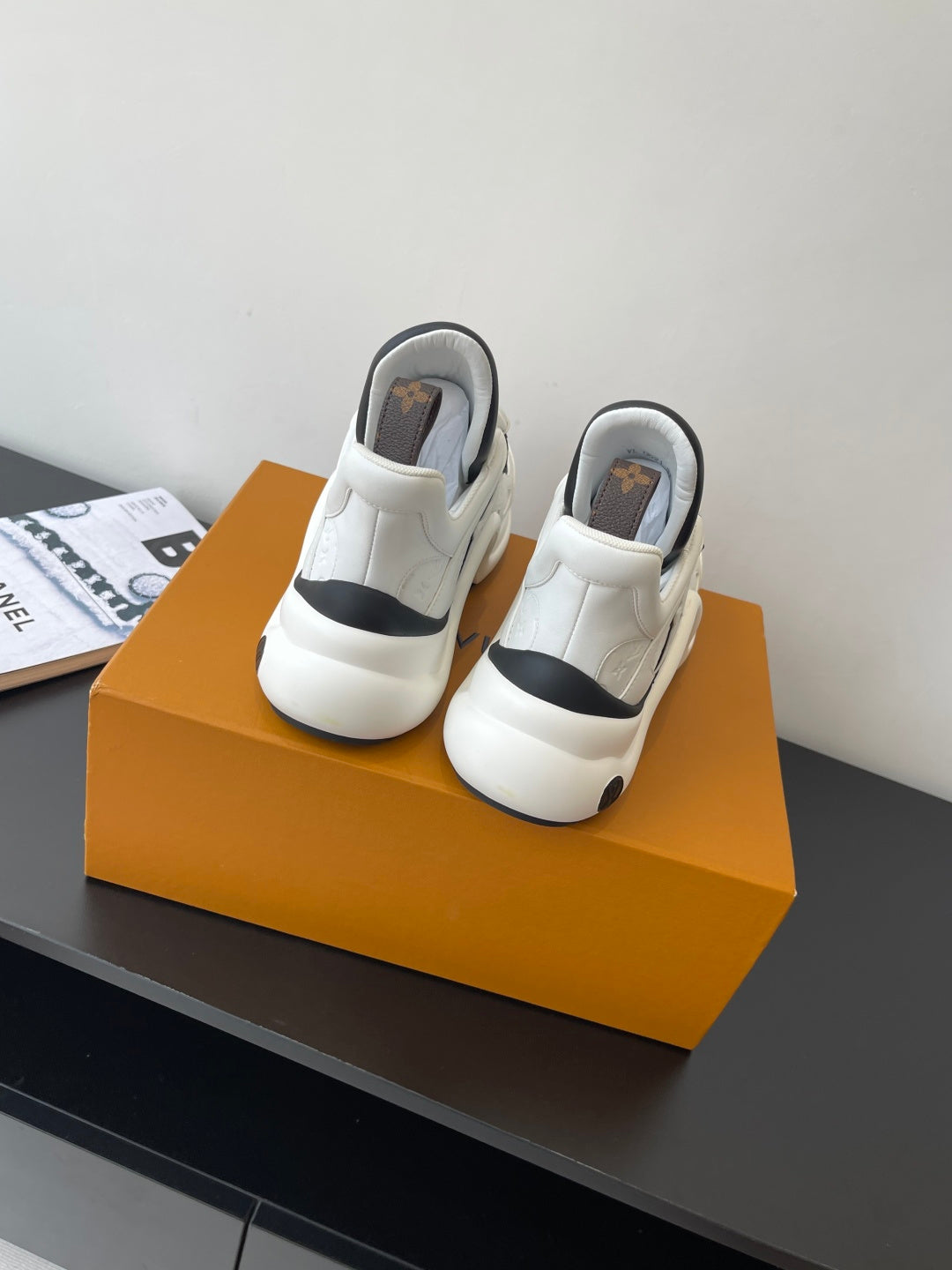 Pair of white sneakers with black heel pull tab and cushioned back collar