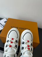 White low-top sneakers with perforated toe and red beaded lace accents