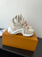 White chunky sneakers, lace-up with red bead accents, raised logo detailing on panels