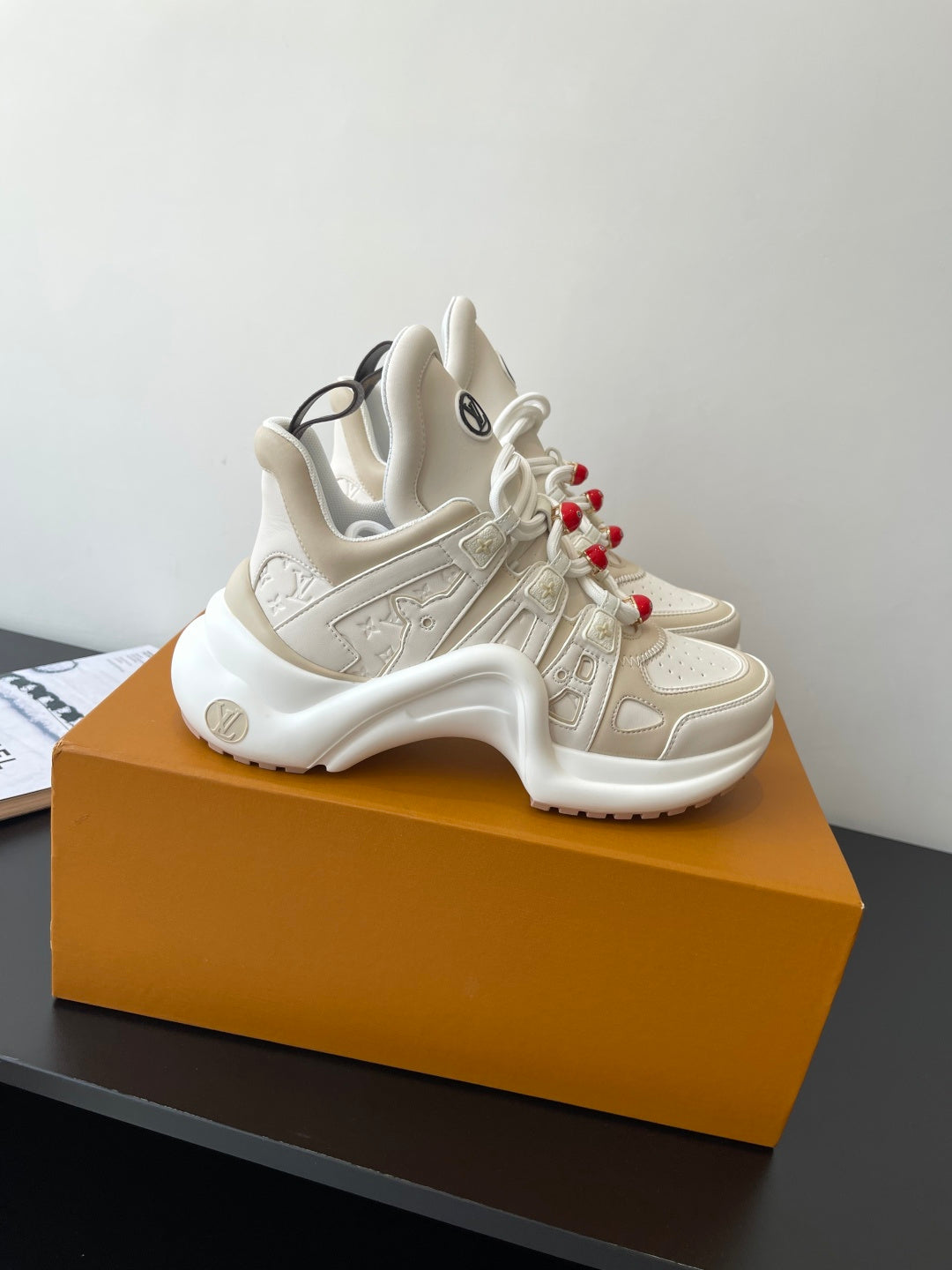 White chunky sneakers, lace-up with red bead accents, raised logo detailing on panels