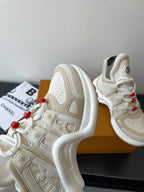 White chunky sneaker with embossed logo patches, lace-up with red bead lace accents