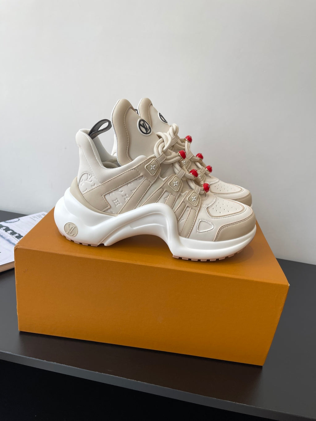 Louis Vuitton women's cream sneakers side view, lace-up with red bead charms