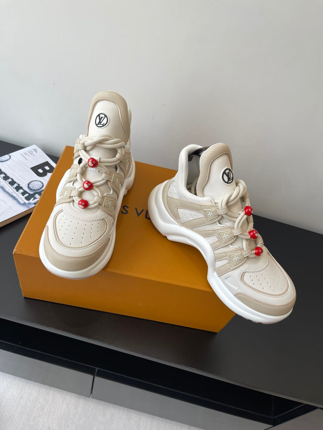 Louis Vuitton women's cream sneakers pair, lace-up with red bead charms and thick sole