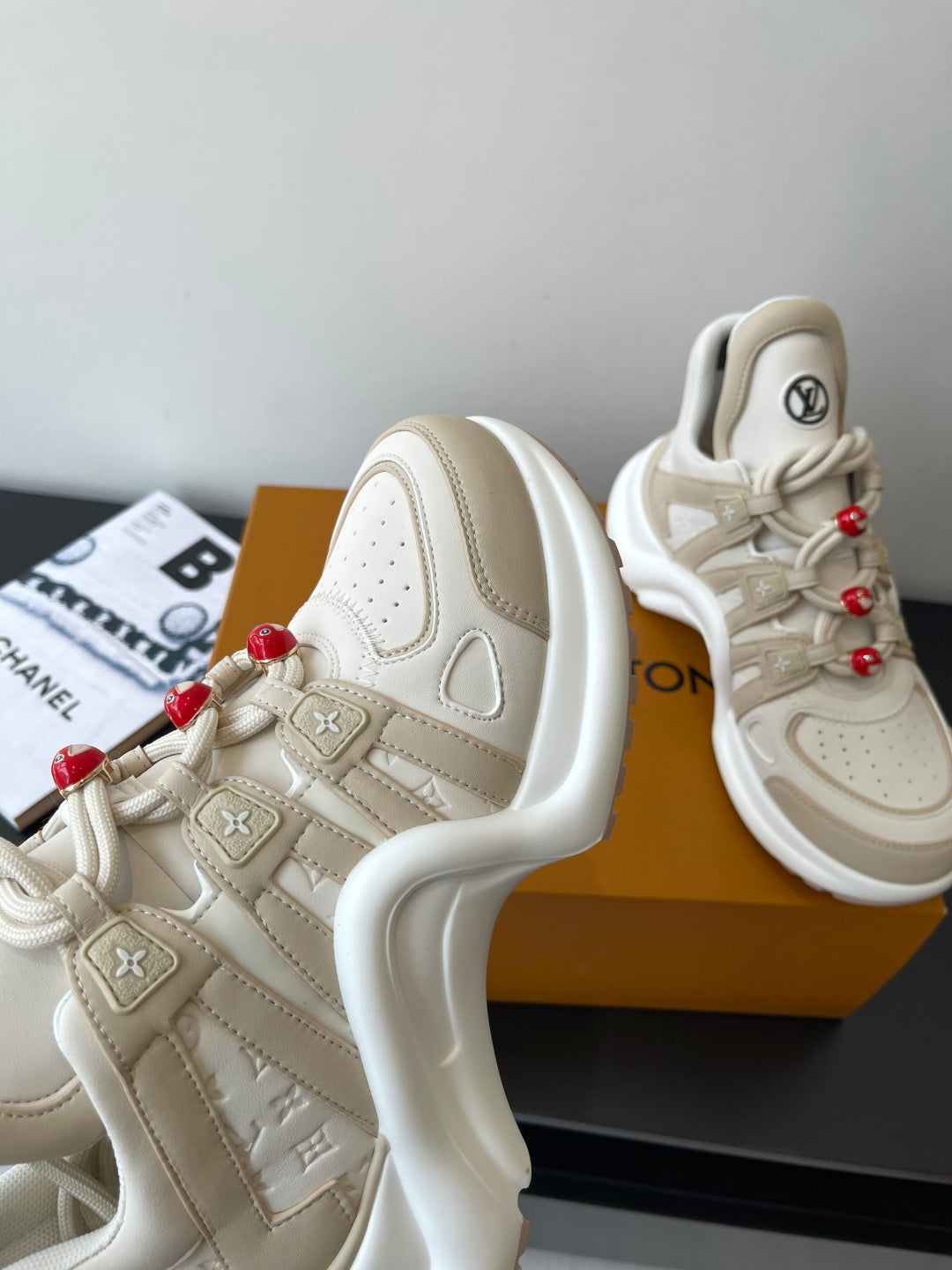 Louis Vuitton women's cream sneakers close-up, side panels and red bead lace charms