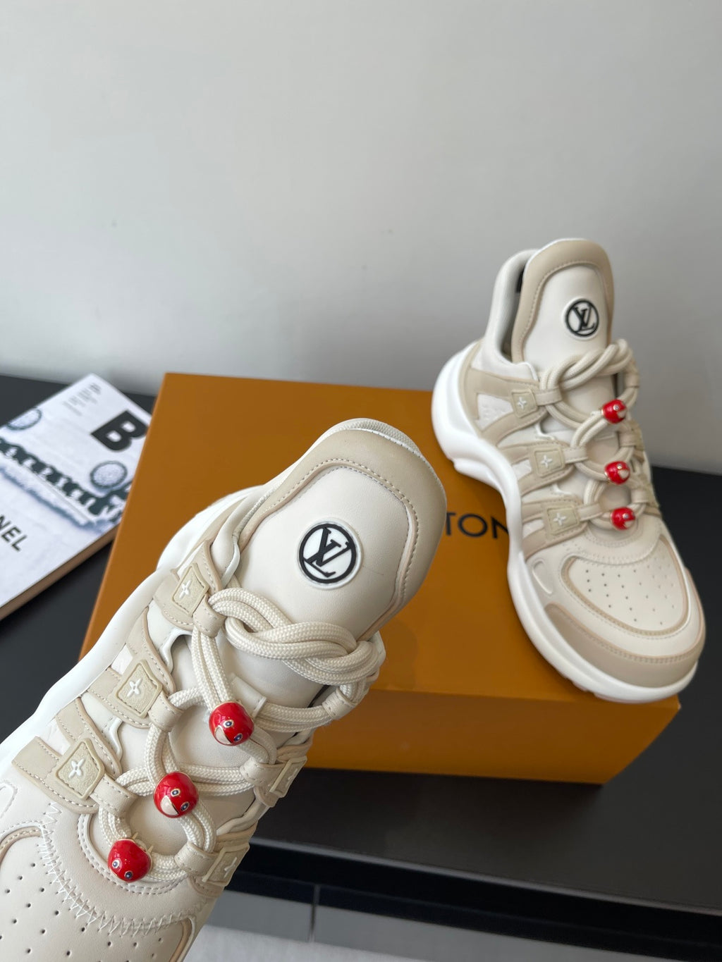 Louis Vuitton women's cream sneaker detail, side logo and red bead lace charms