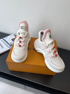 White and pink lace-up sneakers with red pom-poms and LV logos on tongues