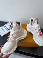 White and pink sneakers with perforated toe, red pom-poms, and LV logos on side