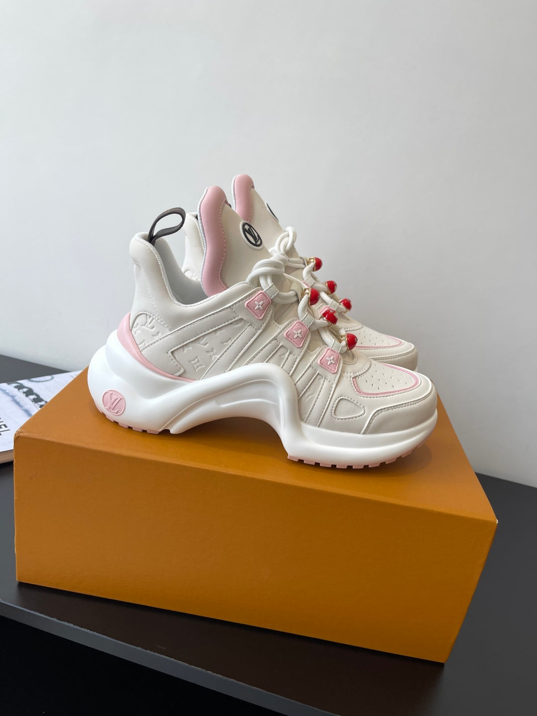White and pink chunky lace-up sneakers with red pom-poms and LV logo patch