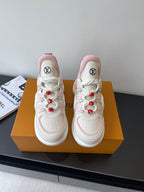 White and pink lace-up sneakers with red pom-poms and LV round logo on tongue