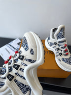 Louis Vuitton women's sneakers side view, white and navy monogram with red lace accents